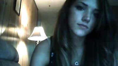 Brunette licks her lips while posing on the couch