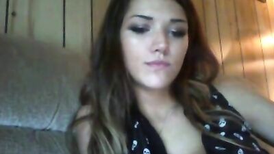 Brunette licks her lips while posing on the couch